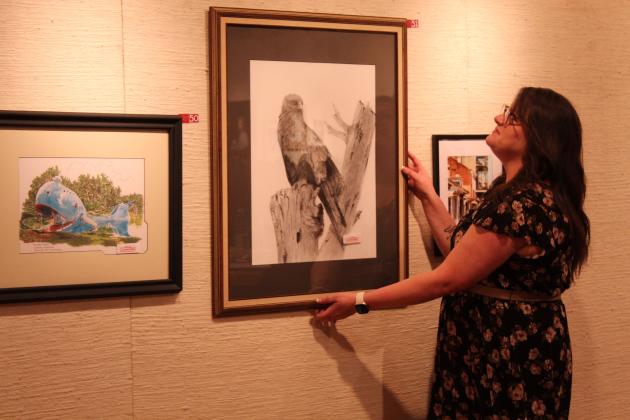 Heather Huff selects a drawing of a hawk by Charles Spillers of Tecumseh at the annual "Off the Wall" event at the Mabee-Gerrer Museum of Art on April 24.