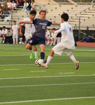 Shawnee's Jax Martin prepares to kick upfield around a Will Rogers player at the April 17 home game. The Wolves won 4-3