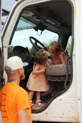Wrynlee Begley, 3, of Tecumseh, sits in the driver's seat of a Canadian Valley Electric Co-op truck and has a moment with her cousin, Elsie Begley, 1, of Meeker, as CVEC Crew Chief Bryce Begley keeps an eye on his daughter and niece. CVEC's truck was one example of heavy equipment at the Touch-A-Truck and Beyond, held at the CPN Festival Grounds on April 11.