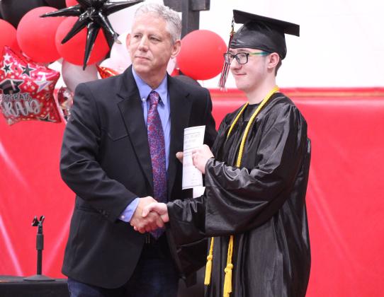 Macomb High School Principal Steve Martin presents an academic scholarship award from East Central University to graduate Jasson Harris-Green during Macomb's Graduation on May 9. Harris-Green was the Salutatorian this year, but Martin spoke about his accomplishments in his place, as Harris-Green chose not to speak. Natasha Dunagan, Countywide &amp; Sun