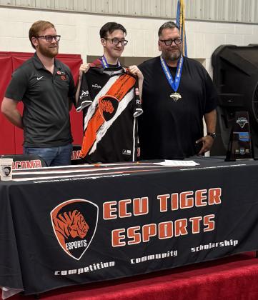Macomb senior Jasson Harris-Green, center, holds up an East Central University jersey after signing with them on May 6 to help start their Esports Chess Team. Also shown are ECU Esports Director Cody Soden, left, and guardian Harvey Kliewer, right. Harris-Green was sought out by Soden after winning the Oklahoma Scholastic Esports Chess State Championship for the second year. Photo provided.