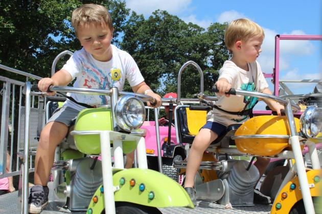 Theodore Leigh and Jack Dockrey, both 4, "drive" their motorcycles at the carnival of the 131st Annual McLoud Blackberry Festival on June 20. The two-day festival also featured vendor booths, live music, kids games and a parade.