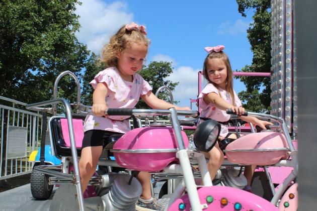 Hazel Kolpin, 3, and Kinsley Kolpin, 5, ride motorcycles at the carnival of the 131st Annual McLoud Blackberry Festival on June 20. The two-day festival also featured vendor booths, live music, kids games and a parade.