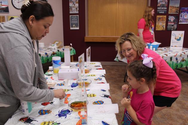 Library Health Coordinator Channah Walker, left, offers three types of honey for Merritt Grace Nichols, 5, of Choctaw, to taste, as Avedis Foundation member Audrey Seeliger of Maud watches during Bugfest at Shawnee Public Library on May 30.