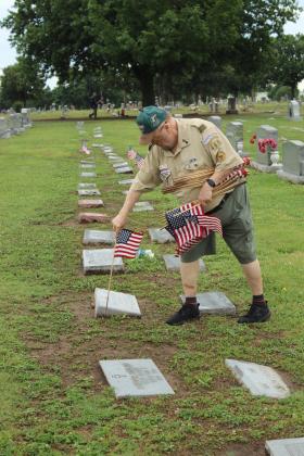 Troop 461 Boy Scout Committee Chair Michael Stearman decorates the graves of veterans at Fairview Cemetery in Shawnee on May 23.