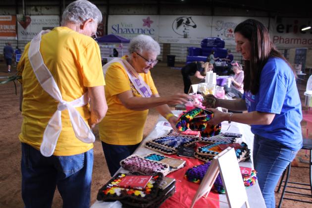 Angie Franklin, right, treasurer on the "Granddad's Compound" team, sells hot pads to cancer survivor Linda Weston during Relay for Life of Pottawatomie County, held at the Heart of Oklahoma Expo Center Fred Humphries Arena on May 29. Weston is with her husband of 61 years, Kenneth Weston, and they have been coming to RFL since 2012. Debbie Davis, mother of RFL organizer Amy Dennis, said she made 50 hot pads (which began as quilt squares) and decided to sell them.