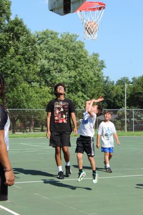 Aaron Nash, 8, of Shawnee, makes a basket, as SHS grad Chevis Sharp, Jr. and Asher McCoy, 8, look on, during the First Annual Hoops for Hope, which was held at the Rotary Briscoe Boy Scout Park on July 25.