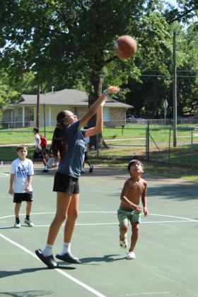 Shawnee eighth-grader Jada Pleets launches the ball, as Dominic Leetka, 7, right, and Aaron Nash, 8, far left, watch during the First Annual Hoops for Hope, which was held at the Rotary Briscoe Boy Scout Park on July 25.