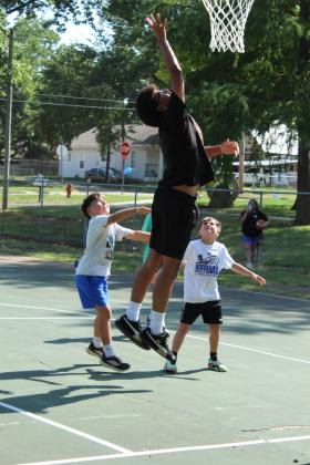 Shawnee High School graduate Chevis Sharp, Jr. makes a layup, as Asher McCoy and Aaron Nash, both 8 and from Shawnee, look on, during the First Annual Hoops for Hope, which was held at the Rotary Briscoe Boy Scout Park on July 25.