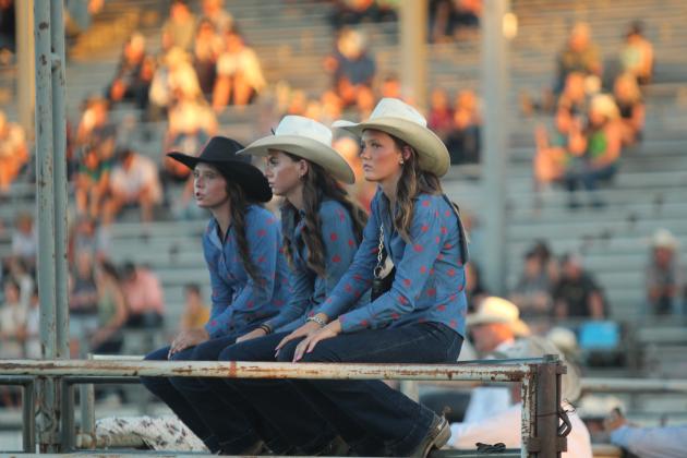 IFYR Contestants Averie Cornell and Dacey Neal, both of Mt. Vernon, TX, and Evie Knox of Dallas, TX, sit on a gate to watch the barrel racing event on July 12.