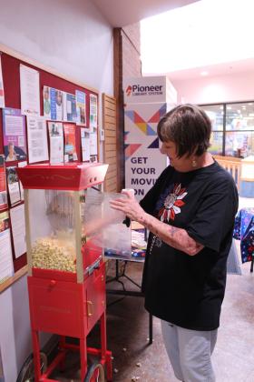 Shawnee Public Library Branch Manager Mary Sims works the popcorn machine during the "Pop In to Celebrate America's 250th Birthday with Popcorn and Ice Cream" event at the library on June 29. In addition to popcorn and ice cream sandwiches, the library also displayed a community tile artwork in honor of the 250th anniversary under a red, white and blue balloon arch.