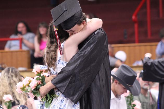 Macomb graduate Hunter Hatler gets a hug from girlfriend Jorja Jones after giving her a pink rose during Macomb HIgh School graduation on May 9.