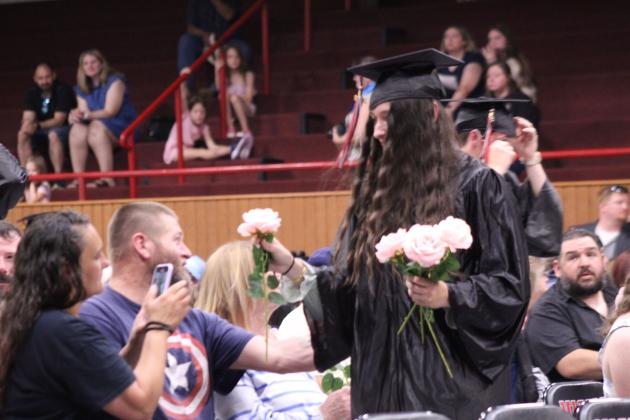 Macomb graduate Shyanne Wano presents pink roses to her parents during graduation on May 9.