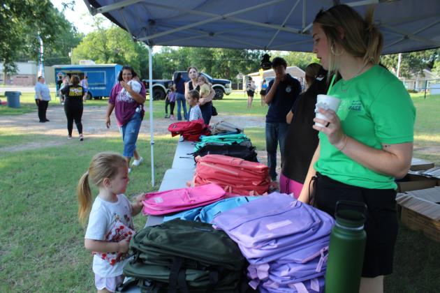 BancFirst employee Devyn Bridges talks with Christyanne Durant, 4, of Harrah, who picks a pink backpack during the Fifth Annual BancFirst Back to School Bash in McLoud on July 23. In addition to backpacks filled with school supplies, BancFirst offered free hotdogs and snow cones from Sno Shak. McLoud FFA members volunteered at the event, as they have every year. The Back to School Bash will be held at Tecumseh's BancFirst next on July 30, 6:15 - 7:30 pm, and at Shawnee's BancFirst on Harrison, Aug. 6.
