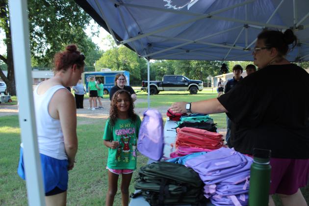 BancFirst employee Hailley Broga hands incoming third-grader, Penelope Delaney, of McLoud, a purple backpack, as mother Elizabeth Delaney looks on, during the Fifth Annual BancFirst Back to School Bash in McLoud on July 23. In addition to backpacks filled with school supplies, BancFirst offered free hotdogs and snow cones from Sno Shak. McLoud FFA members volunteered at the event, as they have every year. The Back to School Bash will be held at Tecumseh's BancFirst next on July 30, 6:15 - 7:30 pm.