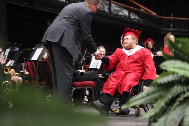 McLoud High School 2026 graduate Corbin Cross shakes hands with Principal Bryan Jennings as he makes his way toward his diploma on May 23.