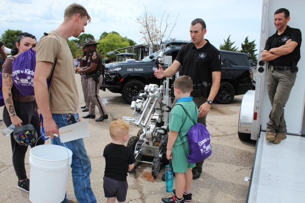 OK Highway Patrol Bomb Squad Trooper Bryce Stout talks to a family about the F6 Robot, as Trooper Lane Gossen looks on, during the Eighth Annual Cops N' Kids, held on Aug. 22 at the Heart of Oklahoma Expo Center. Stout said the robot can be used for observation, moving or spraying suspicious packages, and a variety of other remote uses. The bomb squad also brought an X-ray used to see inside packages.