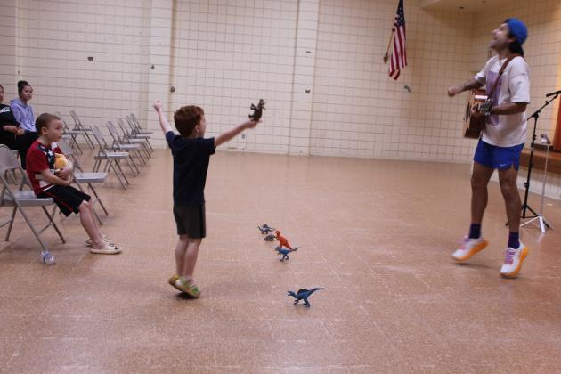 Frankie Lewis, 4, give his best dinosaur roar, along with Syman Hajjar of Hot Toast Music Co, during the "Dinosaur Parade" song at Tecumseh Public Library on July 30.