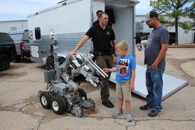 Highway Patrol Trooper Bryce Stout talks with Ricky Morgan, as Kylan Morgan, 8, both of Tecumseh, looks over the F6 Robot.