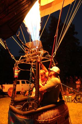 Will Kinser, of Edmond, holds his one-year-old son, Will "Leon" Kinser III, while lighting up his "WayBack" balloon during the balloon glow of the FireLake Fireflight Balloon Festival on Aug. 8. W. Kinser is a third-generation balloon pilot. Natasha Dunagan, Countywide &amp; Sun
