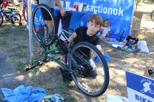 Carson Hall, 8, of Shawnee, washes his bicycle at the Kids Action Empower &amp; Educate booth during the Pottawatomie Go (POGO) Pedal Palooza, held at Rotary Briscoe Boy Scout Park on Sept. 19. In addition to the bike wash, Kids Action offered free helmets and raffled off a bicycle. They partnered with POGO to plan the event.