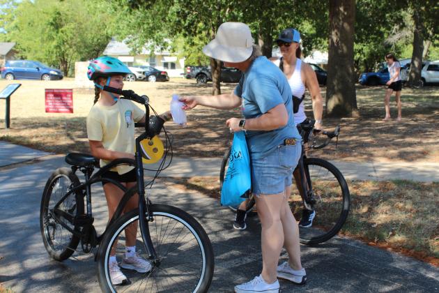 Pottawatomie Go (POGO) volunteer Lindsay Goodson hands out happy face fans and goodie bags from Oklahoma Mobility Management to those finishing the community bike ride during the POGO Pedal Palooza, held at Rotary Briscoe Boy Scout Park on Sept. 19. About 40 people participated, riding on trails around the park. Horace Mann Elementary Principal Christi Lovelady led the ride, along with George Wright from CPN and Ryan Brooks from Uplift Mentoring.
