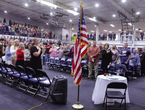 Everyone - including Bethel students, left, and veterans with chairs on the gym floor - stands at attention while the Bethel band plays the national anthem during the Veterans Day Program at Bethel High School on Nov. 11.