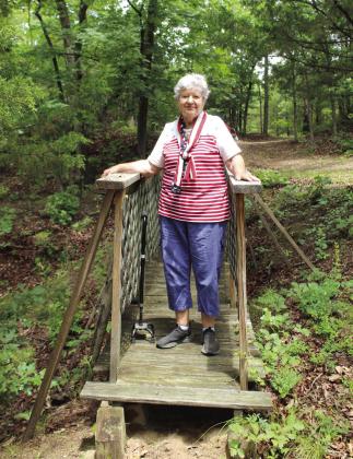 Janet MacMillan stands on a bridge built by her and husband Rich MacMillan, which overlooks a wooded landscape and walking trails at Serenity Hollow Retreat Center, located between Tecumseh and Earlsboro on Kings Road. MacMillan is a licensed professional counselor who welcomes women's groups and special events to their peaceful, 40-acre sanctuary.