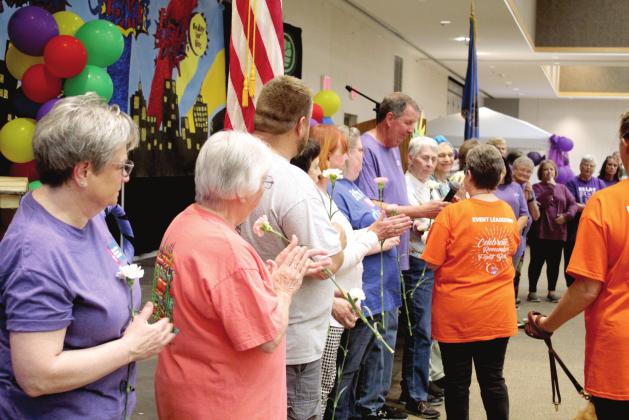 Fellow cancer survivors applaud after Rex Higgins spoke during the Relay for Life, held at the Heart of Oklahoma Conference Center on May 6. Committee Co-Chair Harriet Byers passed along the microphone and handed out carnations to the survivors. At far left, Linda Brown has dealt with six cancer diagnosis in the past 38 years and has been involved in the event since 1989.