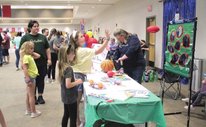 Audrey Vonndran, 9, tries her hand at the football throw at one of the Relay for Life team booths at the Heart of Oklahoma Conference Center on May 6. Booths set up around the center raised money for the American Cancer Society, which invests in cancer research and provides services for those with cancer.