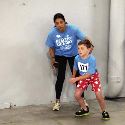 Stage one of the Healthy Kids Day Triathlon was an eight lap race around the gym. Levi Williams, age 7, from Bethel, was guided by YMCA's Ana Rose.
