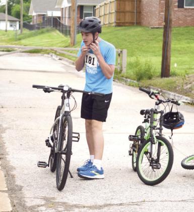 First to finish the foot race, Liam Tilley, age 12, from Byng, straps on his helmet to prepare for stage two: the eight-lap biking race in the parking lot. Liam is the grandson of Valarie and Randy Colburn of Shawnee.
