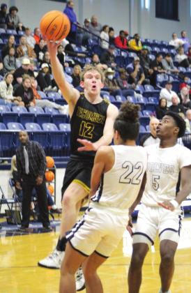 Tecumseh’s Ben Corley scores two points over Shawnee’s Jalen Wicks (#22) and T.J. Bishop (#5) during the third quarter of the game at Shawnee on Jan. 14. Corley made nine points in that quarter and 21 points for the game.