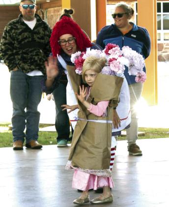 During Shawnee's Fall Fest on Nov. 1, Emma Hilton, 5, of Tecumseh, waves to the Costume Contest judges - Jamie Sacco, with the City of Shawnee, Cpl. Vivian Lozano, and State Rep. Dell Kerbs - in the 4-7-year division, as Sue Ellen Frerichs assists her. Hilton won Most Creative in her division, "Little Ghouls." There was also a pet costume contest and the "Spooky Stars" for ages 9-13.