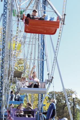 A woman waves from the ferris wheel, which was rented for Shawnee's Fall Fest. Everything except the food vendor's items were free to the public.