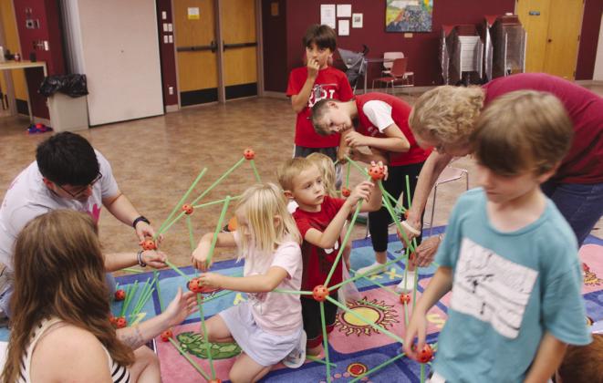 Children's Librarian Jairo Montelongo, along with Cody Swarny and Janie Ogle, help children in the Shawnee Public Library's "STEAM Kids" program to create a glow-in-the-dark fort out of plastic rods and orbs on June 26. Julie Moring, the Children's Department Manager at Shawnee, said they have 251 people signed up for their Summer Learning Challenge, which is up from 219 last year. The program runs through Aug. 15, and she said there is still time to register.