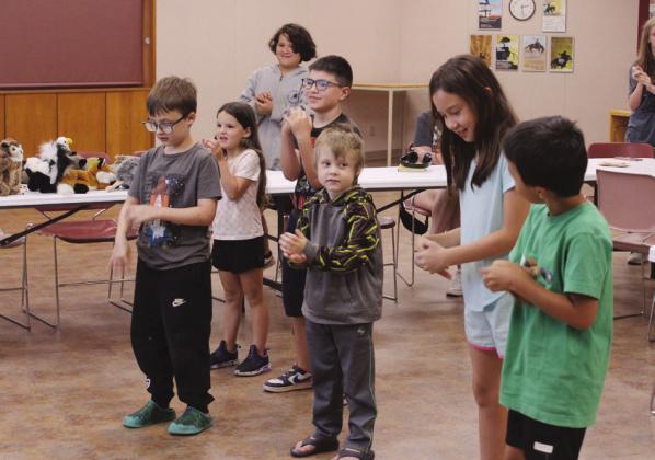Children pretend to be raccoons washing their hands during "Mammals in Your Back Yard."