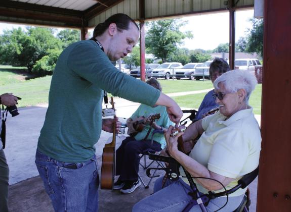 Aaron Pence, with the Norman branch of Pioneer Library System, instructs Barbara Harrison on the right string to hold on the ukulele on June 24 at Slick Humphrey Park in Tecumseh. Carolyn McGraw and Mary Hightower are also shown. Pence had about six pupils for the ukulele lesson and also shared his percussion instruments.