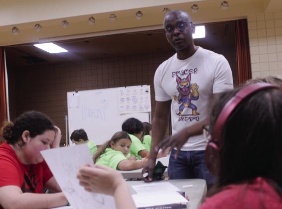 Artist Danny Gordon comments on the art of Harper Pierce, 12, of Tecumseh, during the Teen Cartooning class at Tecumseh Public Library on July 2.