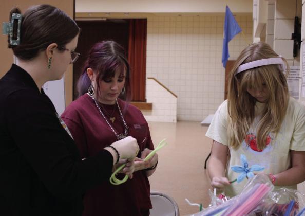 Tecumseh librarian Caitlyn Love helps 4-H Club members Mya Sadler and Addison Bristow to make pipe cleaner flowers during '4-H Maker Day,' Aug. 5, at the Tecumseh Public Library/City Hall Auditorium. In addition to flowers, 22 4-H members designed and engraved metal water bottles
