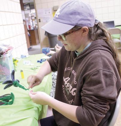Tecumseh 4-H Club member Izabelle Tucker creates a pipe cleaner flower during '4-H Maker Day,' Aug. 5, at the Tecumseh Public Library/ City Hall Auditorium. In addition to flowers, 22 4-H members designed and engraved metal water bottles and beaded bookmarks.