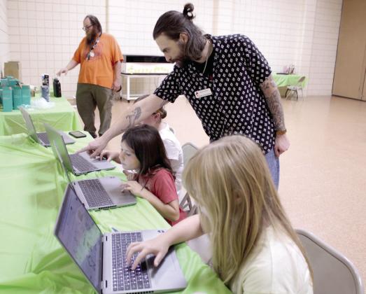 Tanner Chambers, a computer training center assistant from Pioneer Library System in Norman, helps three 4-H Club members to pick out designs for engraving metal water bottles during '4-H Maker Day,' Aug. 5, at the Tecumseh Public Library/City Hall Auditorium.