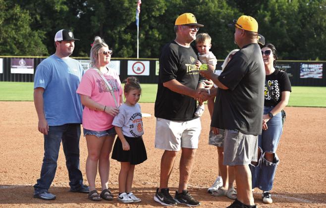 Tecumseh Fast Pitch Softball Head Coach Chad Trahan, surrounded by family, receives a game ball from Assistant Coach Perry Wilson to commemorate coaching 500 wins at the home game on Sept. 16. Photo courtesy of Kenetta Lisenbee