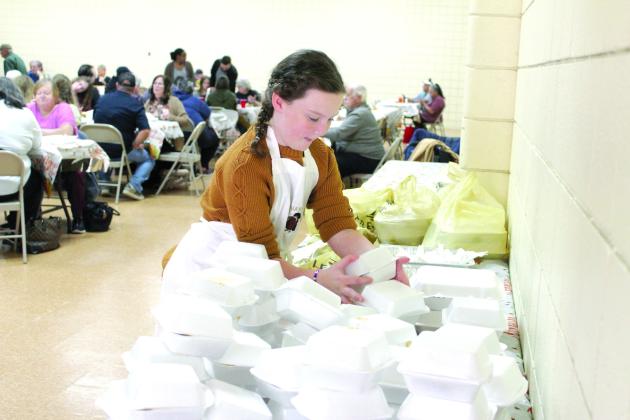 Taycie Baker stacks up boxed slices of pie for to-go meals at the 18th Annual Tecumseh Family Thanksgiving Dinner at Tecumseh City Hall Auditorium. Event organizer and Baker’s grandmother Suzanne Gilbert said they gave out 625 to-go dinners and 500 dine-in meals for a total of 1,125 this year. Countywide &amp; Sun/Natasha Dunagan