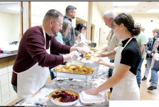 Aaron O’Rorke adds rolls and cranberry sauce to a meal for Katie Overstreet to deliver to a table during the 18th Annual Tecumseh Family Thanksgiving Dinner at Tecumseh City Hall Auditorium on Nov. 23. Also volunteering are Matt Goodson, behind Overstreet, and from left, Rita Goodson, Jordan Baker, Taycie Baker, Annie Jo Gilbert and Dustie Baker.
