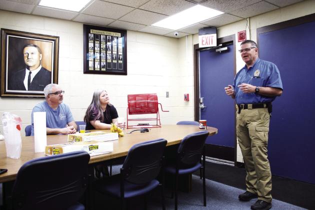 Tecumseh Police Chief J.R. Kidney speaks during the Tecumseh Chamber of Commerce monthly TAG meeting, May 11, as Anthony LaGrange and Kimberly Elliott listen. Behind them is a painting of fallen Police Chief Grover Butler, painted by retired detective Charles Spillers. Countywide &amp; Sun/Natasha Dunagan