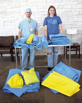 Surgical Supply Technician Brice Koons and Bethel senior Cadence Treece pose with the sleeping mats, tarps and bags made from disposable surgical instrument wraps at SSM Health St. Anthony Hospital in Shawnee on Oct. 20. Treece picks up the wraps from Koons each week, and her mother, Richelle, sews them. The Treeces made their first donation of eight adult sleeping mats, six pet mats, three child mats, 29 bags, one pillow, and two tarps to the St. Benedict's Catholic Church Community Breakfast on Oct. 22.