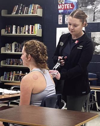Faith Sly, from Athletico, demonstrates a physical therapy technique called “cupping,” on Tecumseh High School Student Intern, Laycee Thoma, during the carreer fair held at Tecumseh High School on Feb. 25. Adelaide Lack, Intern, Countywide &amp;amp; Sun
