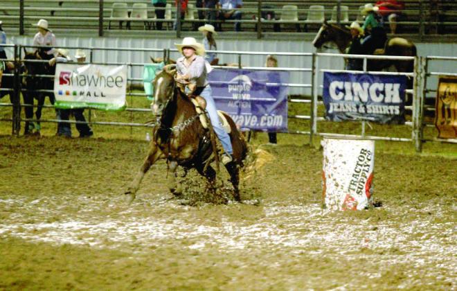 Danni Brown of Bethel steers her horse through the mud around the second barrel at the IFYR on the evening of July 15.