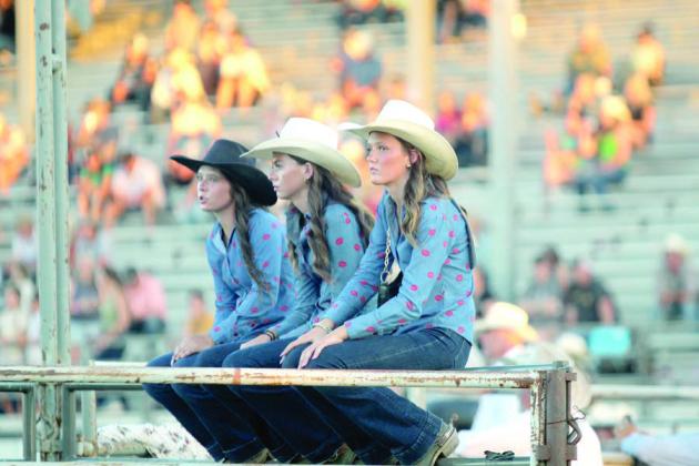 IFYR Contestants Averie Cornell and Dacey Neal, both of Mt. Vernon, TX, and Evie Knox of Dallas, TX, sit on a gate to watch the barrel racing event on July 12.